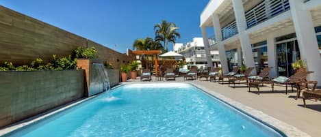 Een buitenzwembad, ligstoelen bij het zwembad