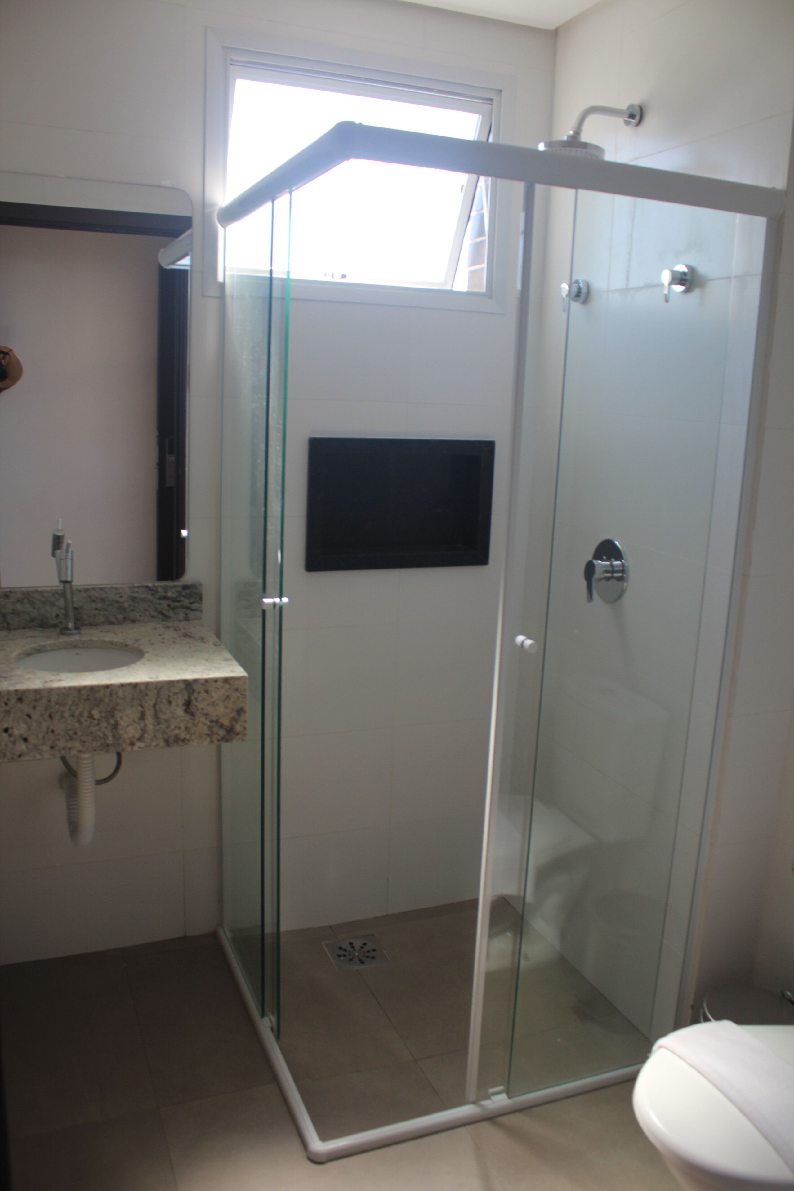 A bathroom with a glass-enclosed shower, a sink with a marble countertop, and a toilet.