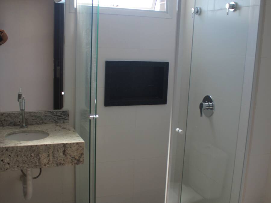 A bathroom with a glass-enclosed shower, a sink with a marble countertop, and a toilet.