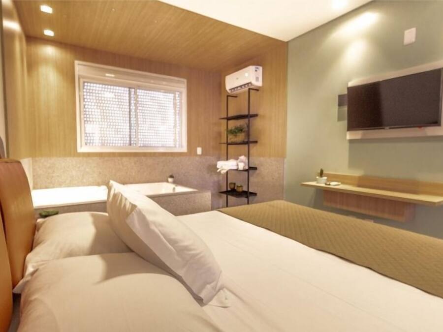 Una habitación de hotel con una cama, una ventana, un lavamanos y un televisor.