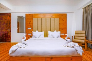 A neatly made bed with a wooden headboard, two pillows, and a folded towel on the side. - TIH Hotel Sky Desert (Leh)