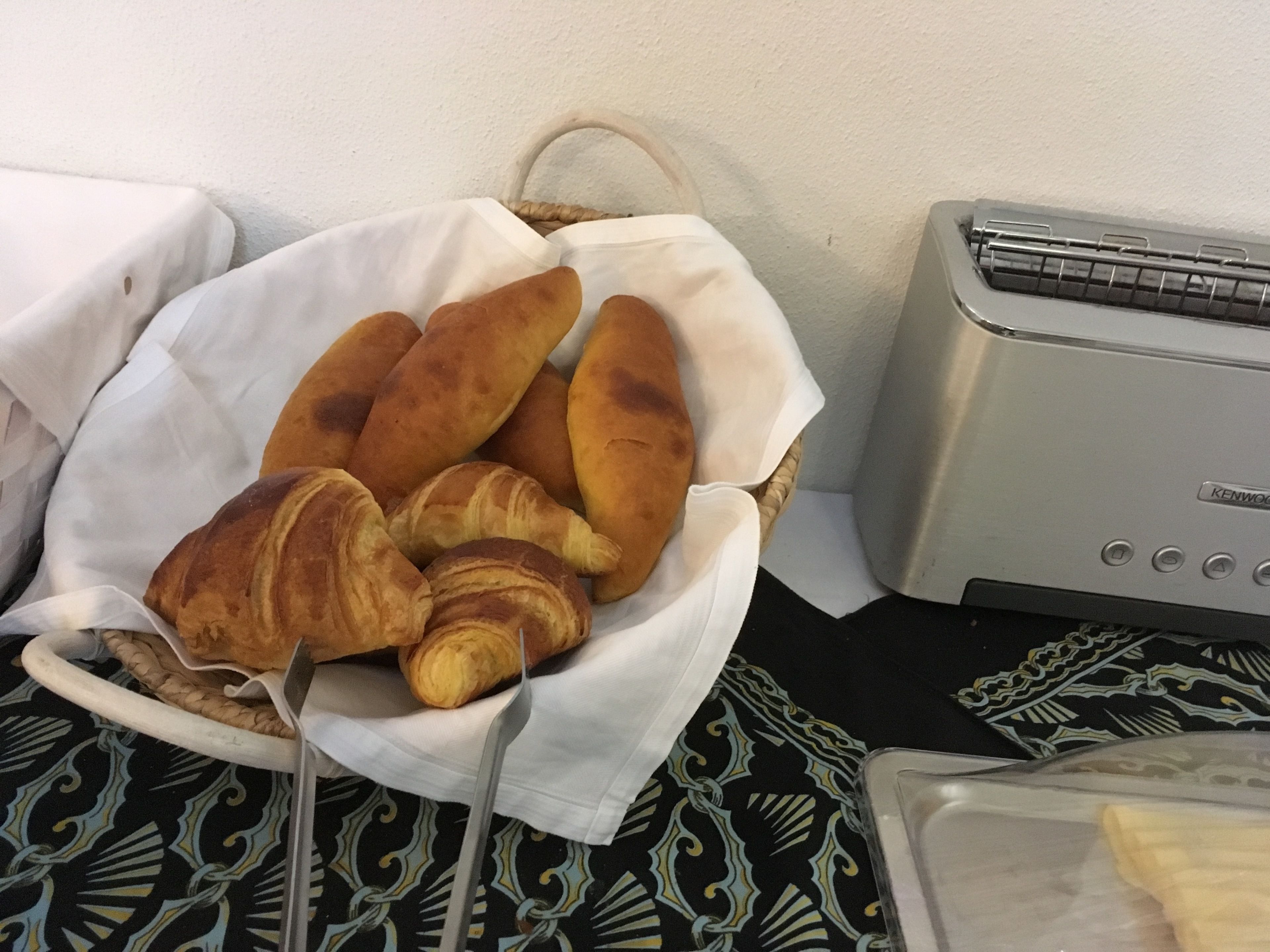 Una cesta de pan y un tostador sobre una mesa.