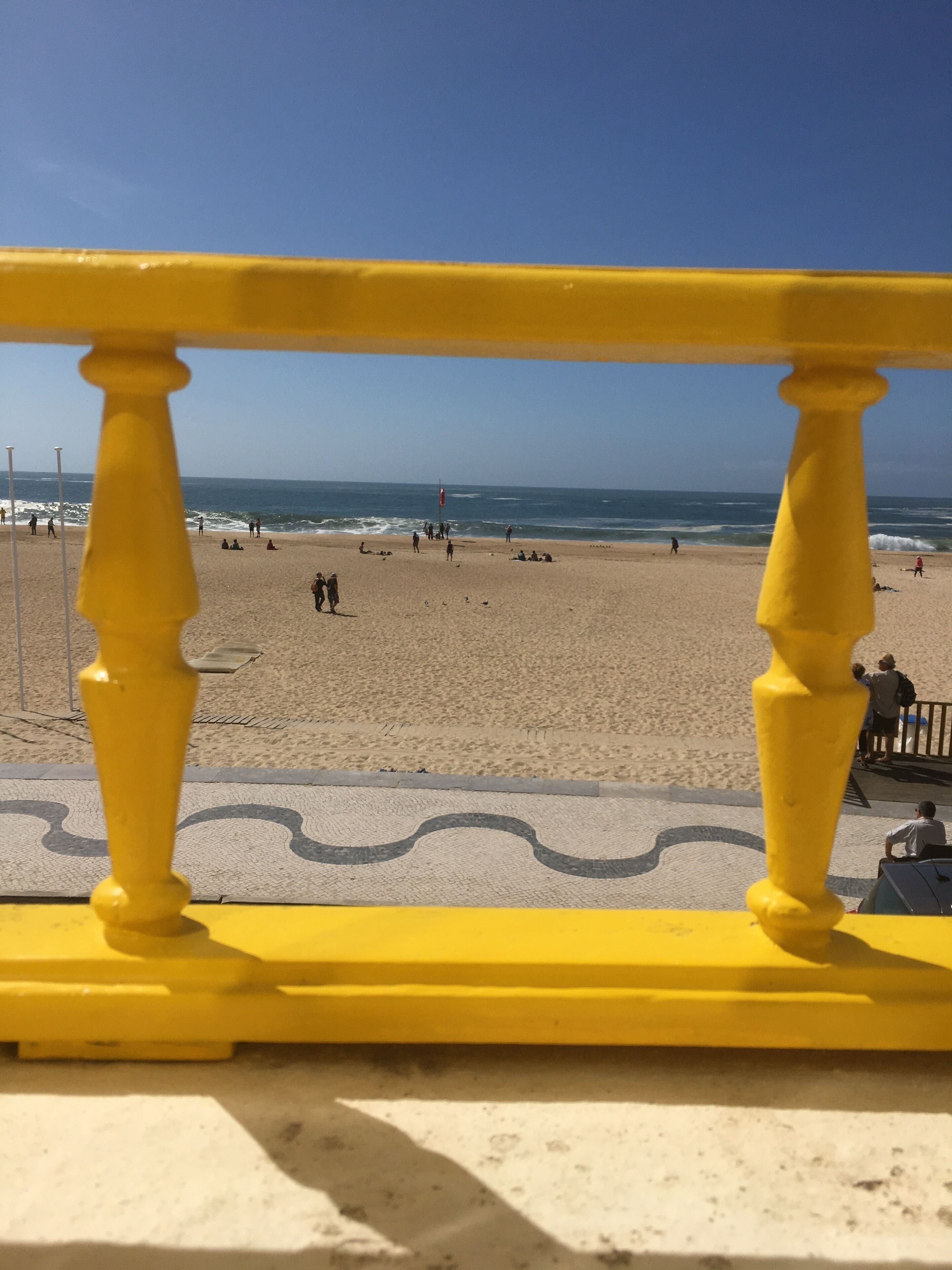 A beach with a yellow railing in the foreground.