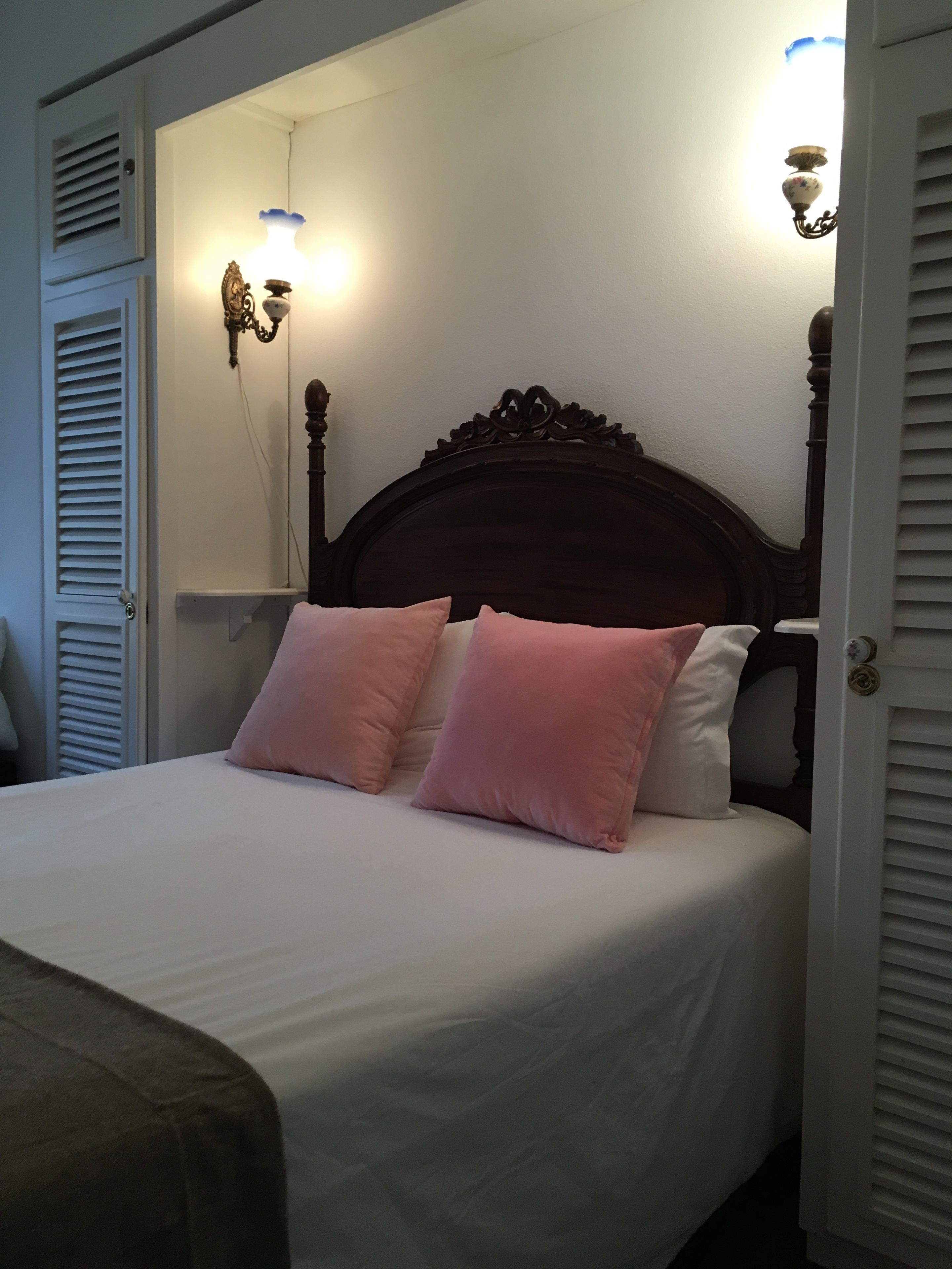 A neatly made bed with two pink pillows and a wooden headboard.