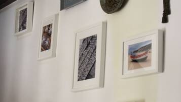 A staircase with a wooden handrail and a white wall with framed pictures and a wall sconce.
