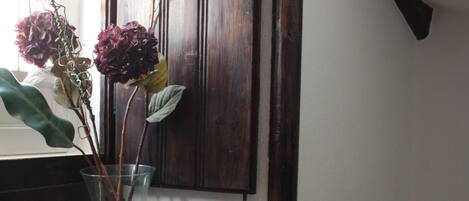 Una escalera con escalones de madera y un jarrón de vidrio con flores secas sobre un repisa de madera.