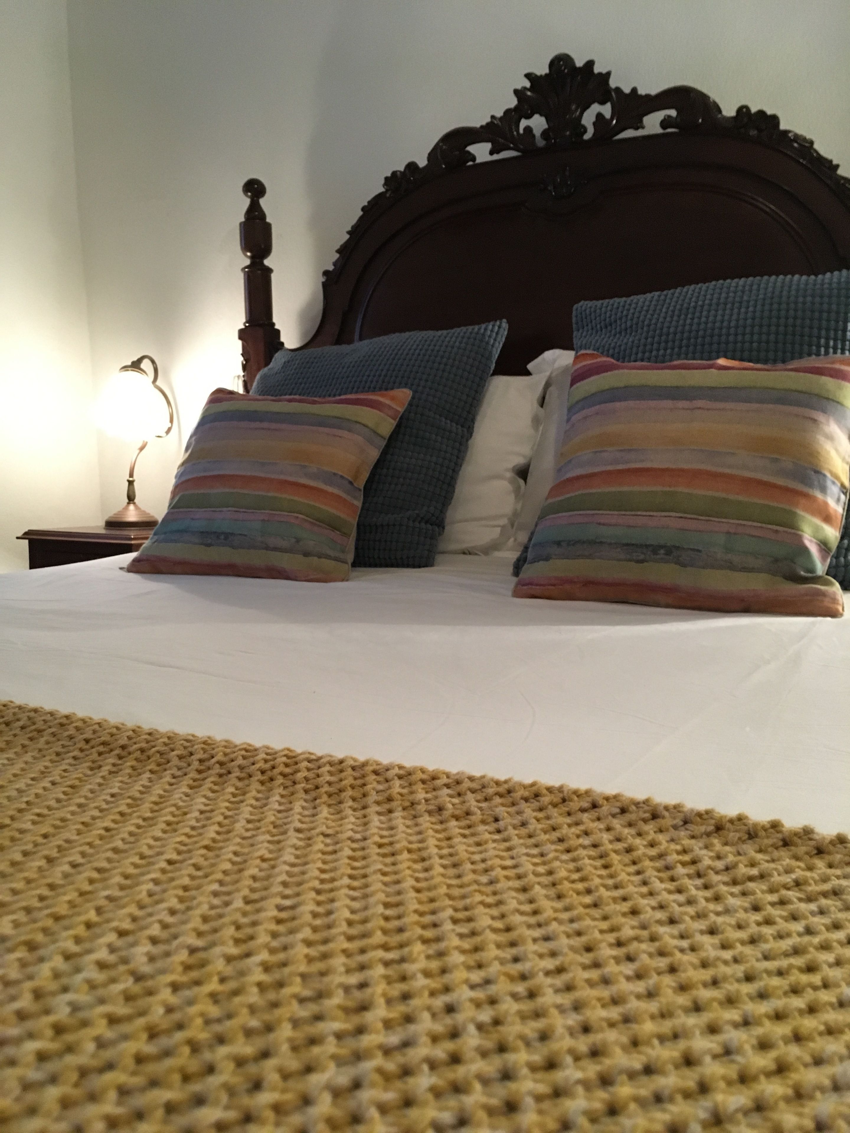 A bed with a striped pillow, a plain pillow, and a blue pillow.