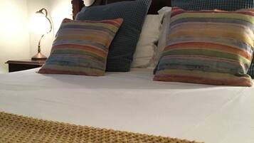 A bed with a striped pillow, a plain pillow, and a blue pillow.