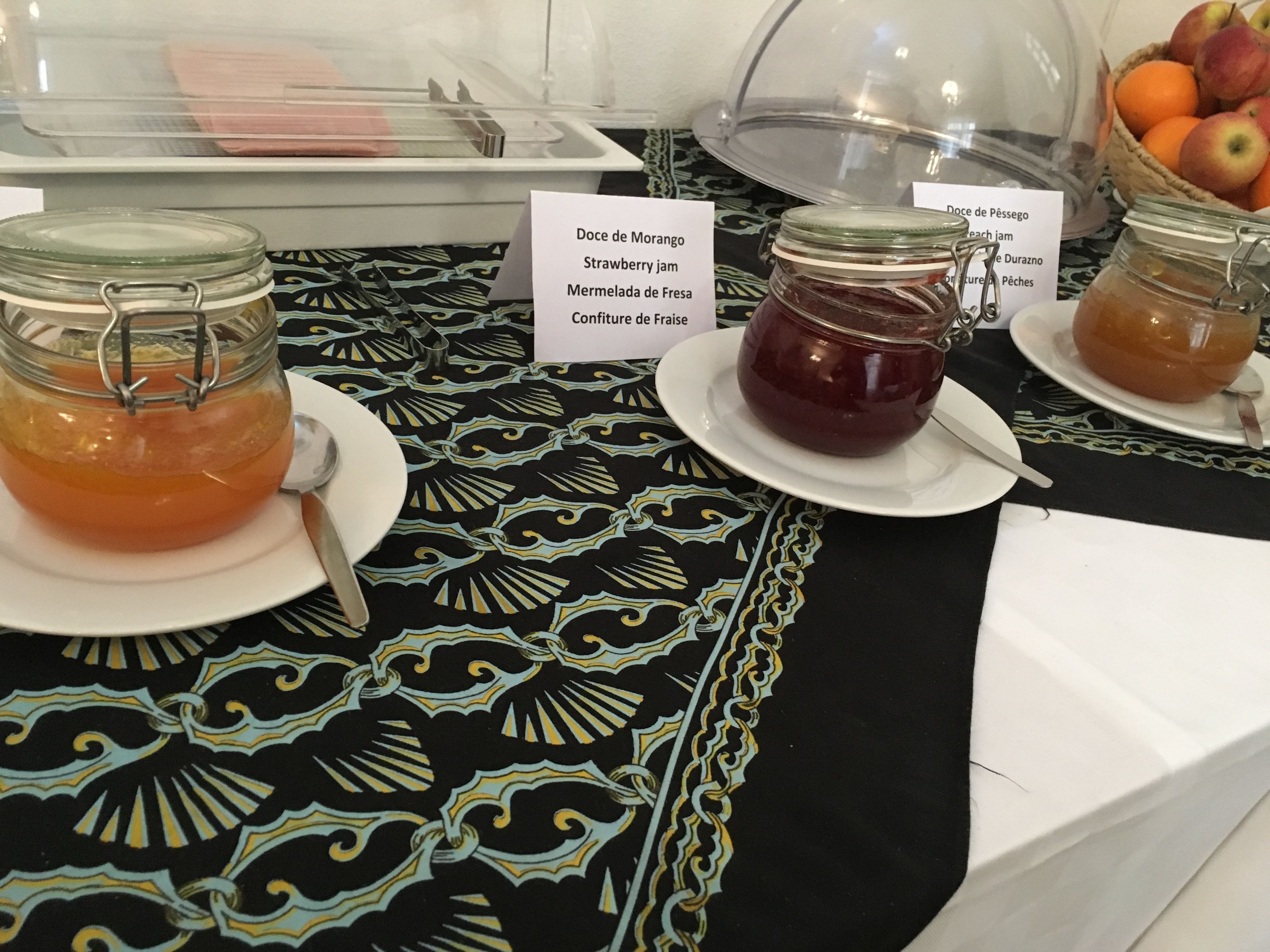Un buffet de petit-déjeuner avec des pots de confiture et un saladier de fruits.