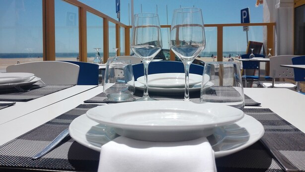 A table set for dining with a view of the beach and ocean. - Hotel Ribamar (Nazaré)