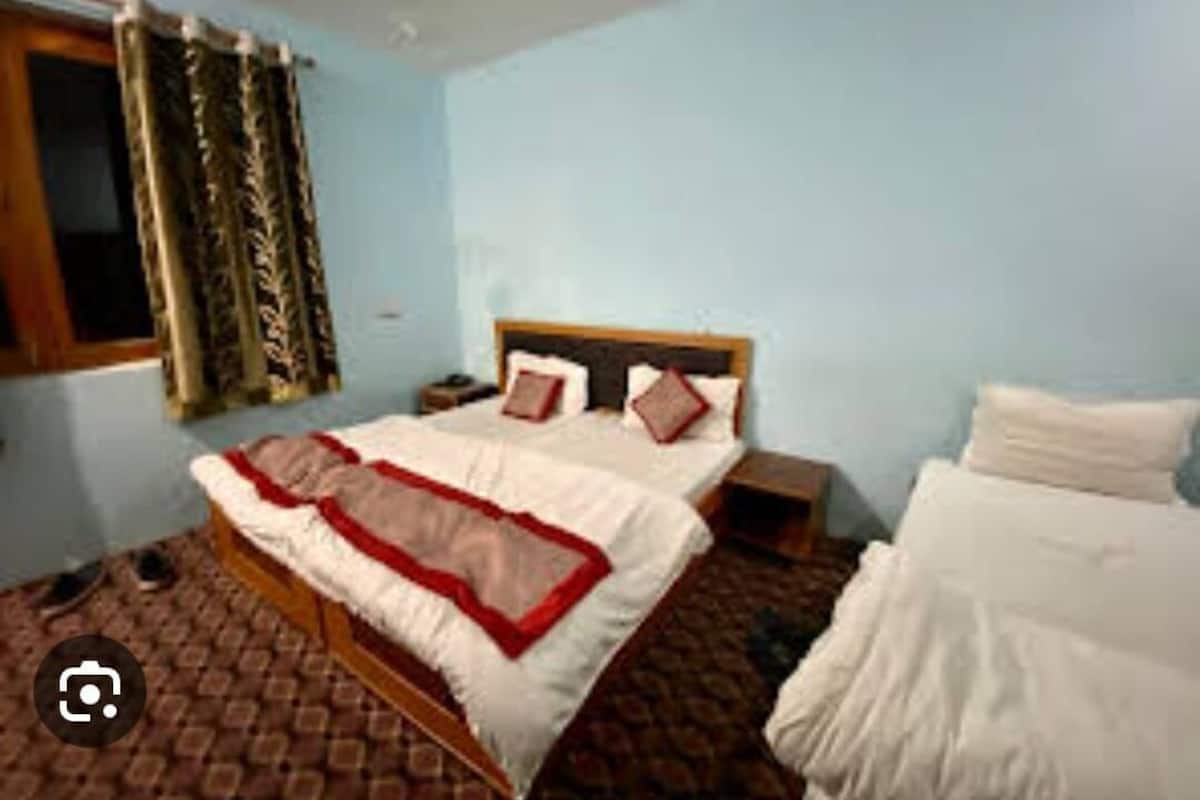 Un dormitorio con cama, mesita de noche y ventana con cortinas.