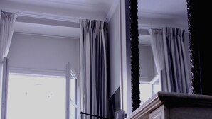 A room with a fireplace, a patterned armchair, and a view of the outside. - Hôtel de Tourny (Bordeaux)