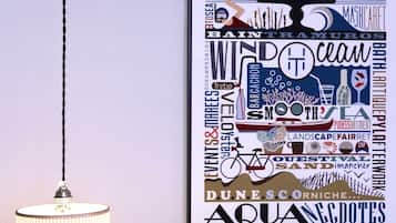 A wall with a framed poster featuring various words and phrases, a hanging light fixture, and a plain wall.