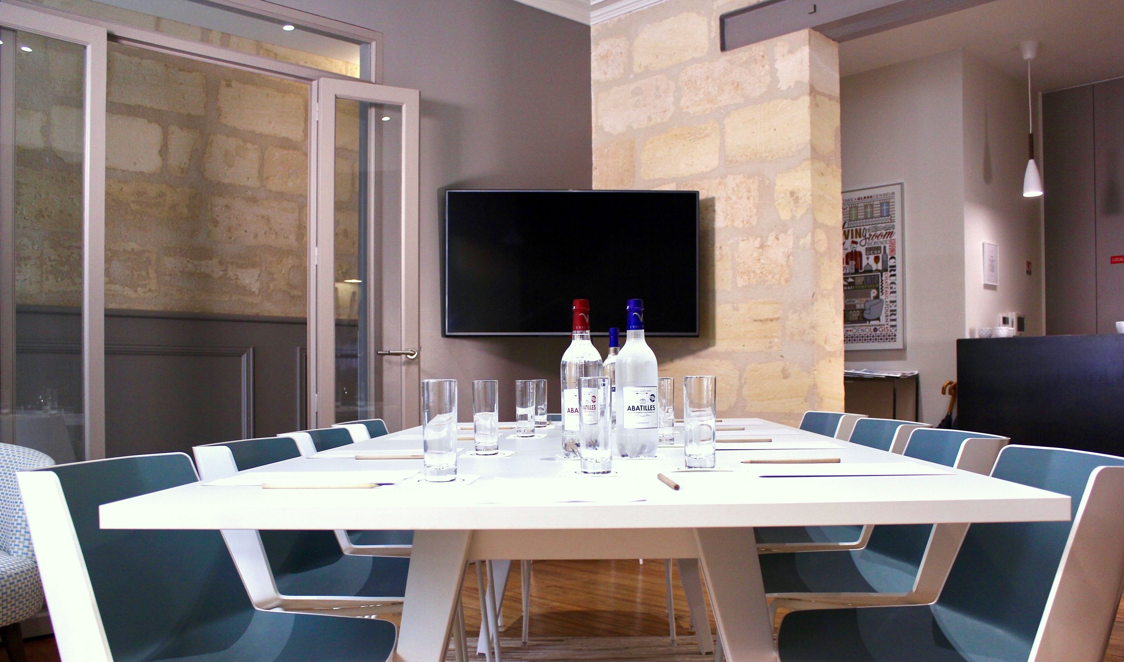 A conference room with a long table, chairs, and a flat-screen TV on the wall.