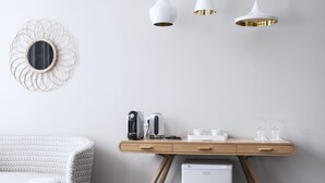A modern room with a wooden desk, a white refrigerator, and a patterned ottoman. - Hôtel de Tourny (Bordeaux)