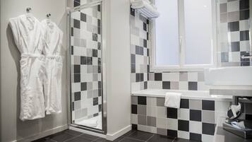 A modern bathroom with a checkered tile backsplash, a glass shower enclosure, and a white sink with a towel on the counter.