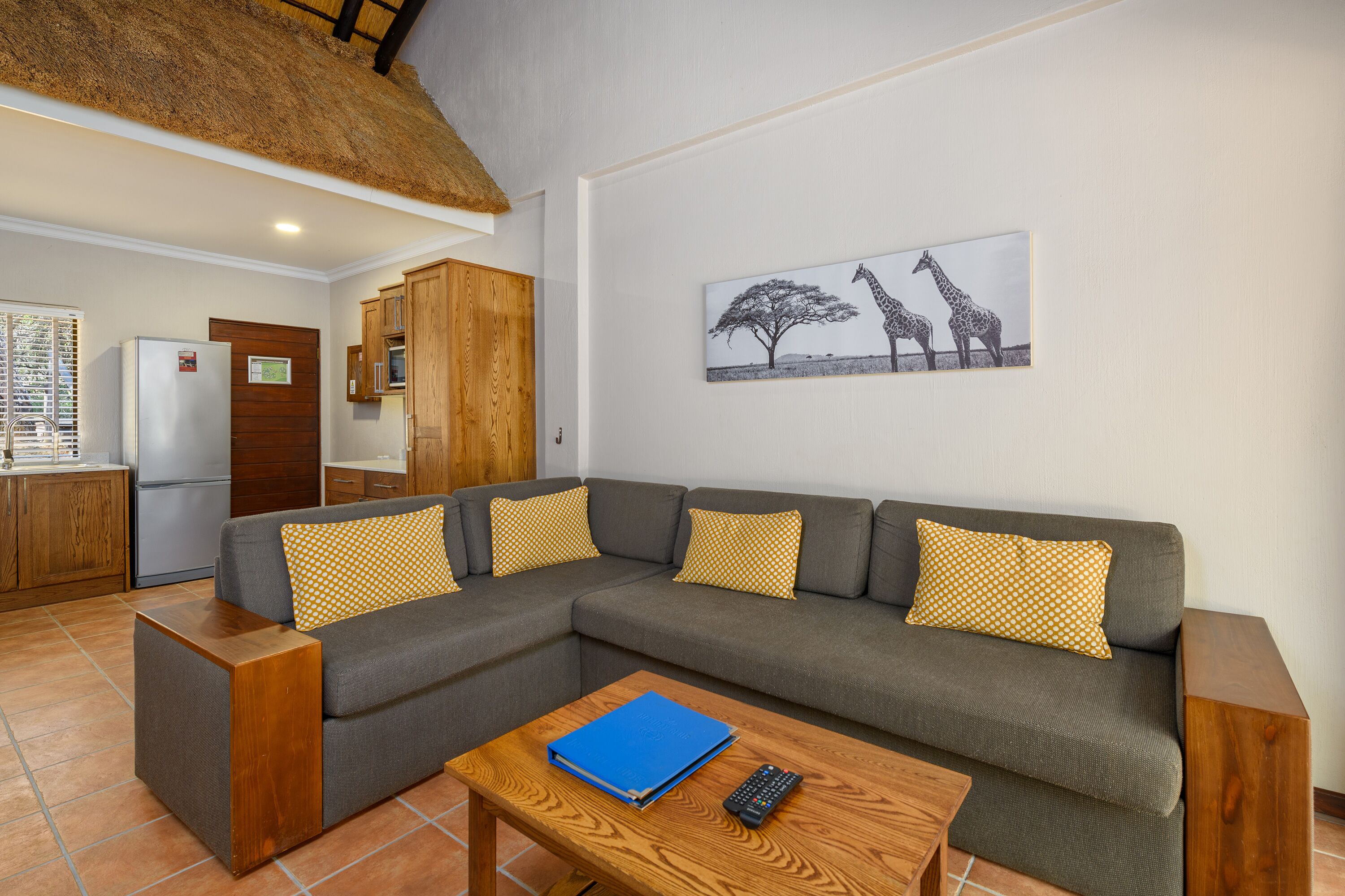 A living room with a grey sofa, wooden side tables, a blue folder, and a remote control.