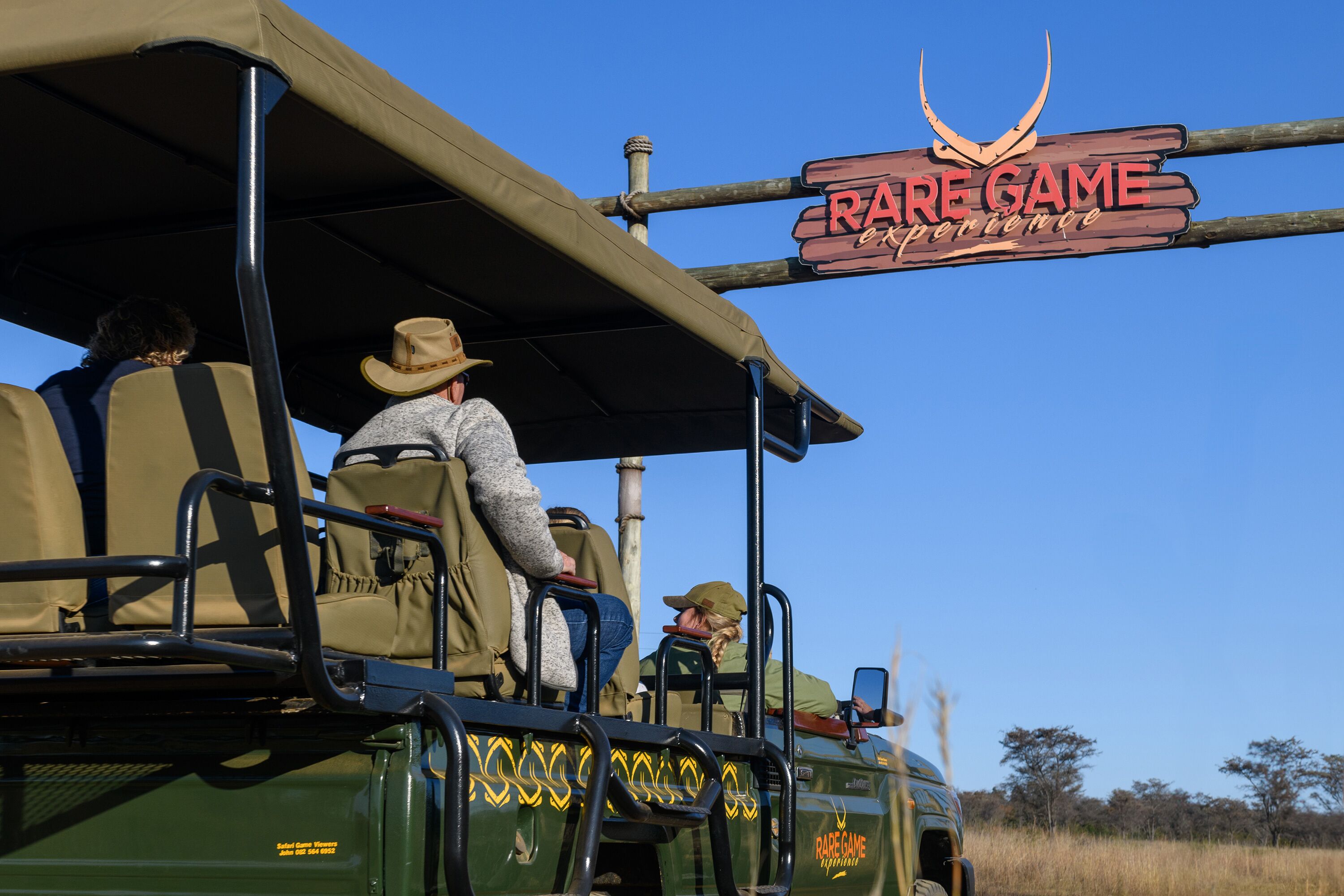 A safari vehicle with a sign reading "RARE GAME EXPERIENCE" and passengers inside.