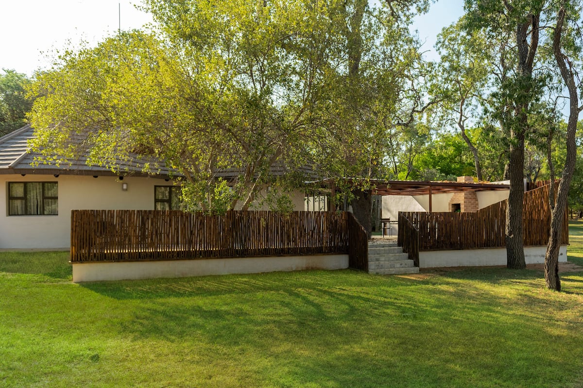 A house with a fenced yard, a wooden deck, and a small staircase leading to a covered area.