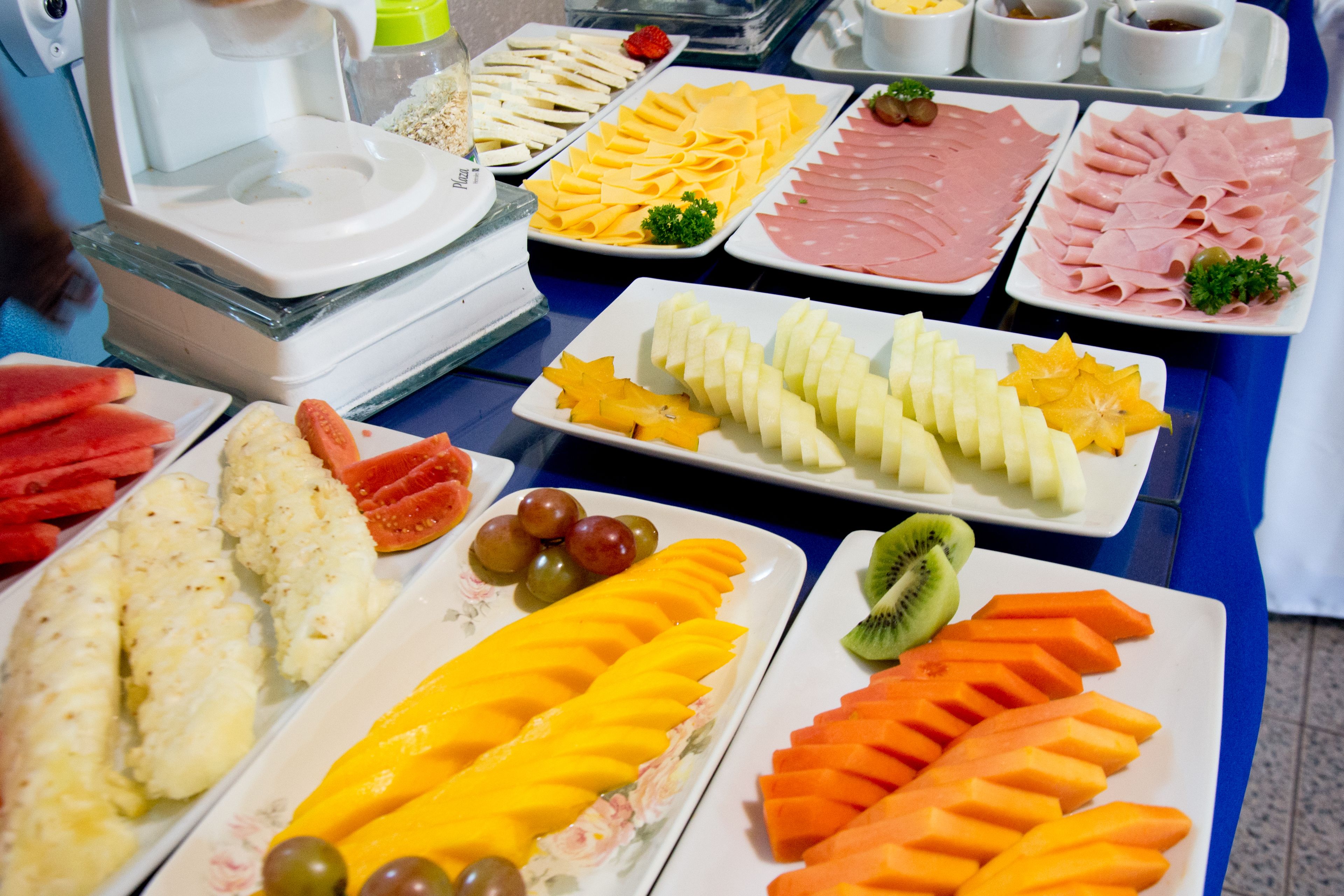 A buffet table with various food items including fruits, cheeses, and meats.