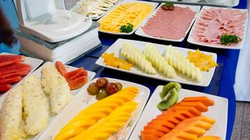 A buffet table with various food items including fruits, cheeses, and meats.