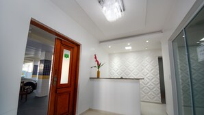 A reception area with a wooden door, a reception desk, and a patterned wall. - Mar e Mar Florianópolis (Florianópolis)