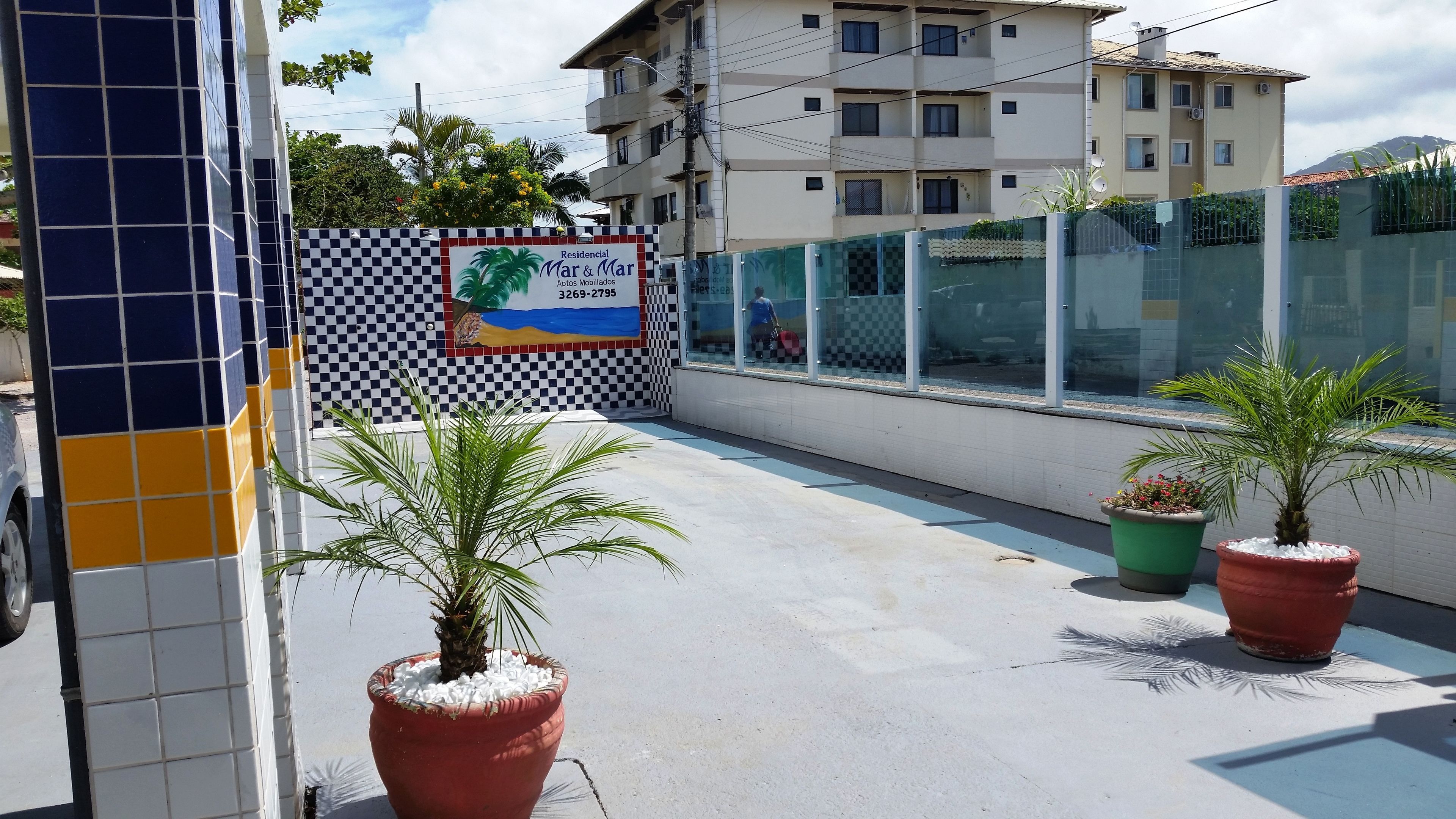 Edificio residencial con pared a cuadros, plantas en macetas y un cartel que anuncia alquiler de casas móviles.