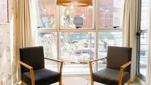 A room with two dark armchairs, a small round table, and a large window with curtains. - Feel Buenos Aires (Buenos Aires)