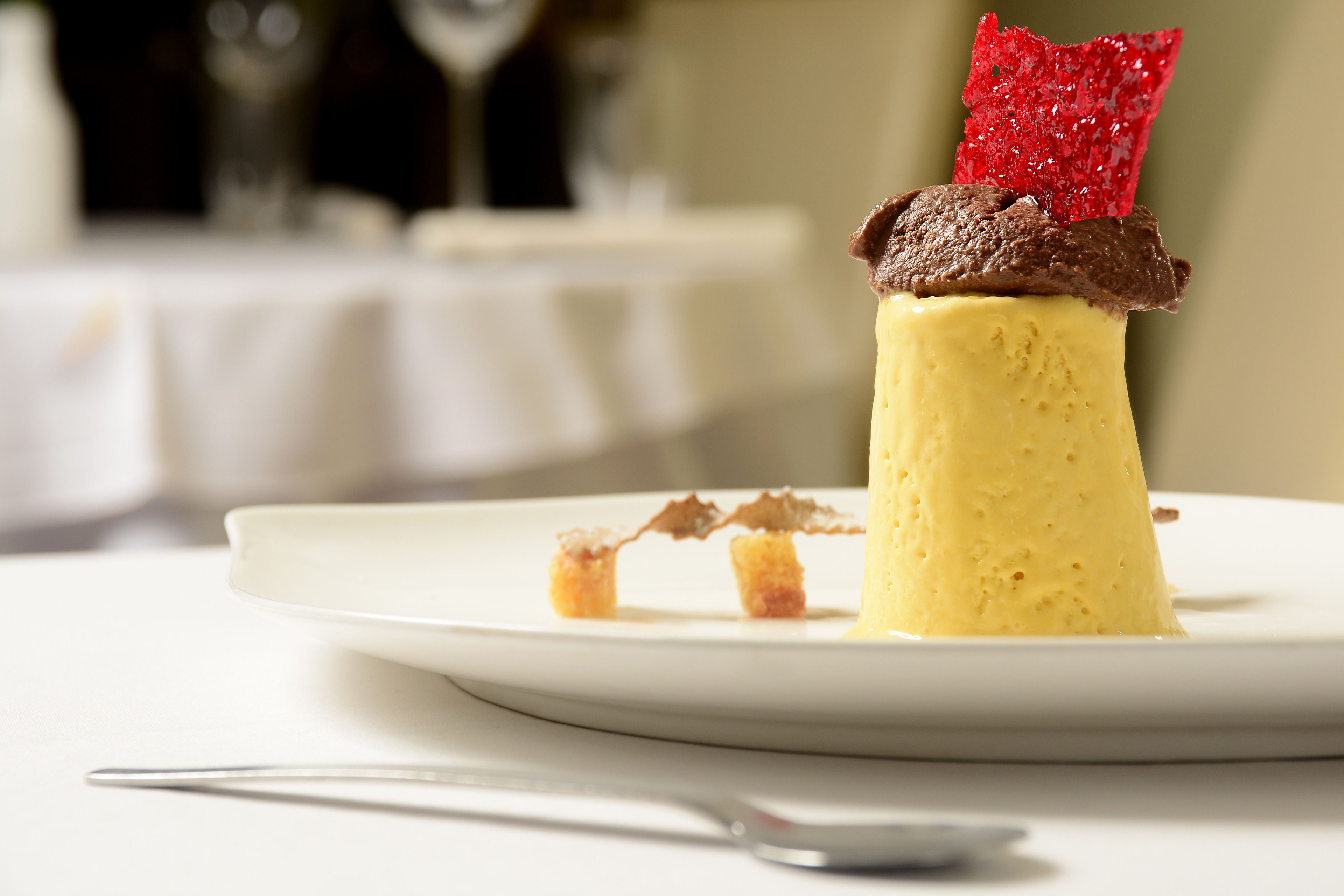 A dessert on a white plate with a spoon beside it.