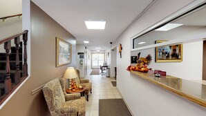 Een hotelgang met gestreept fauteuils, een bureau met lamp en lijstwerken aan de muren.