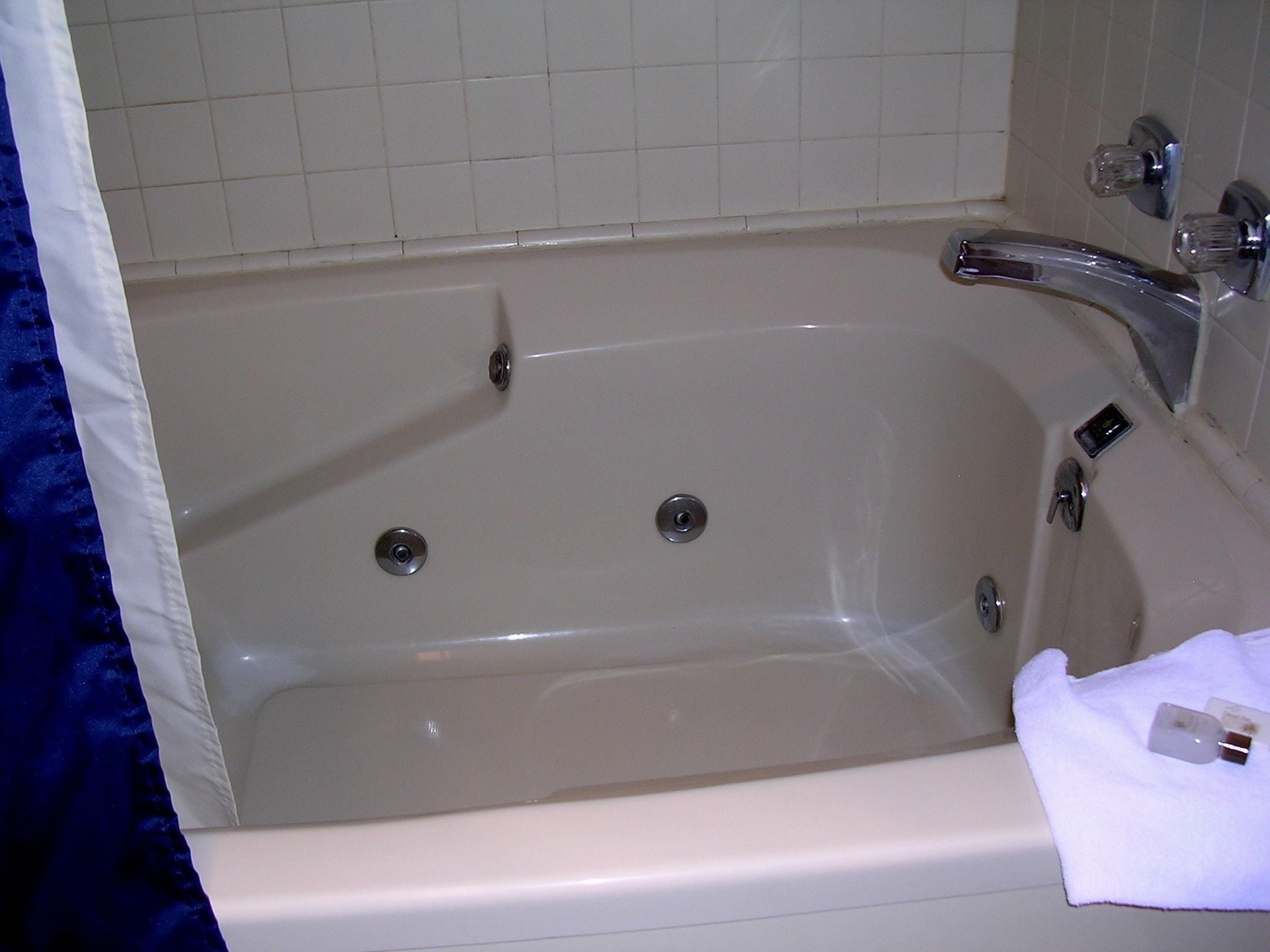 A standard white bathtub with a chrome faucet and two drain holes.