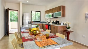A modern kitchen with granite countertops, stainless steel appliances, and wooden cabinets. - Ana's Village (Tulum)