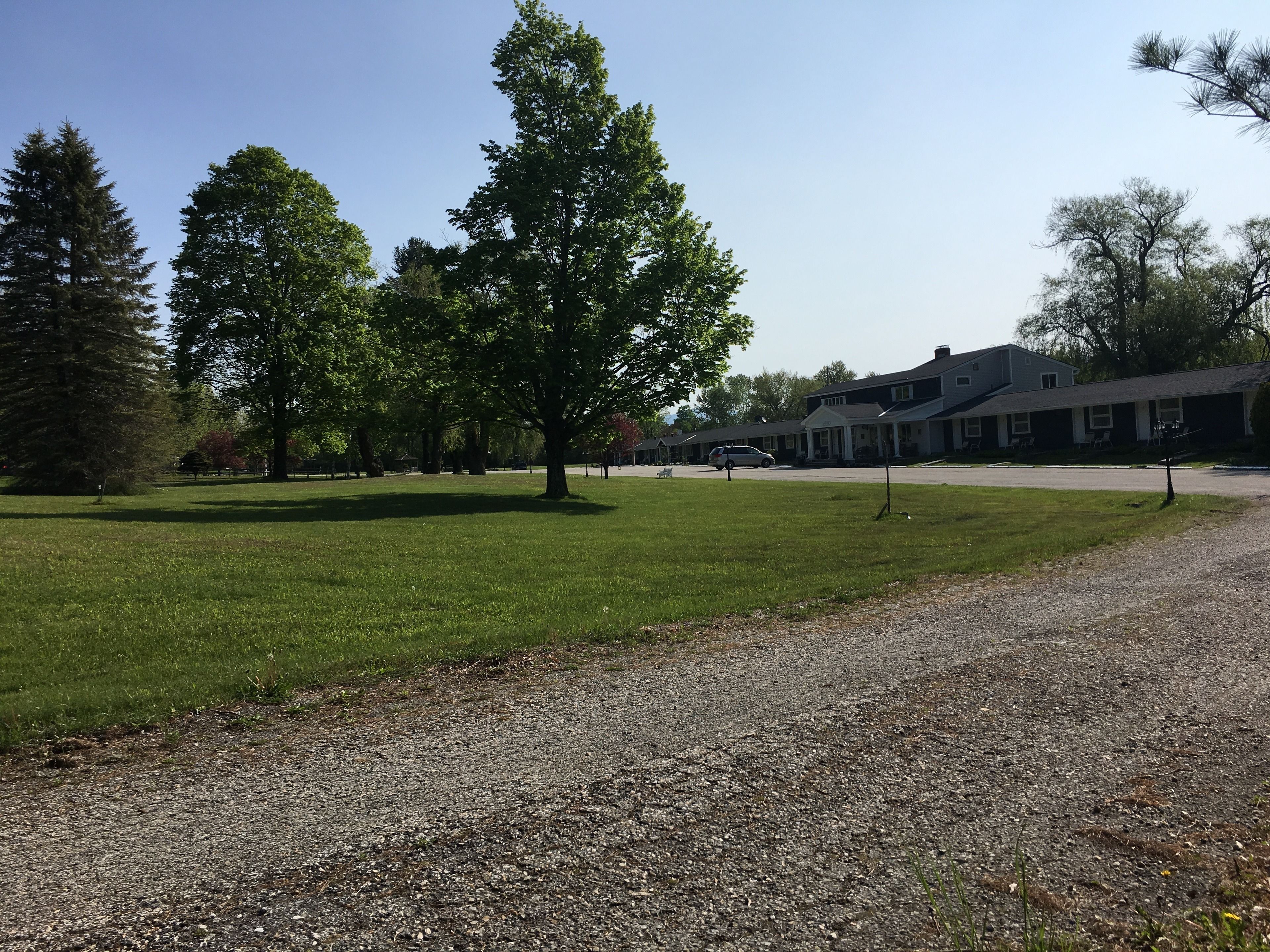 A grassy area with a gravel path leading to a building with a porch.