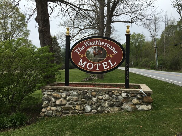 A sign for The Weathervine Motel with a stone base and decorative elements.