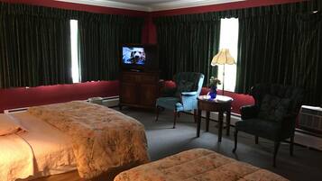 Quarto de hotel com duas camas, televisão, cadeira, mesa e abajur.