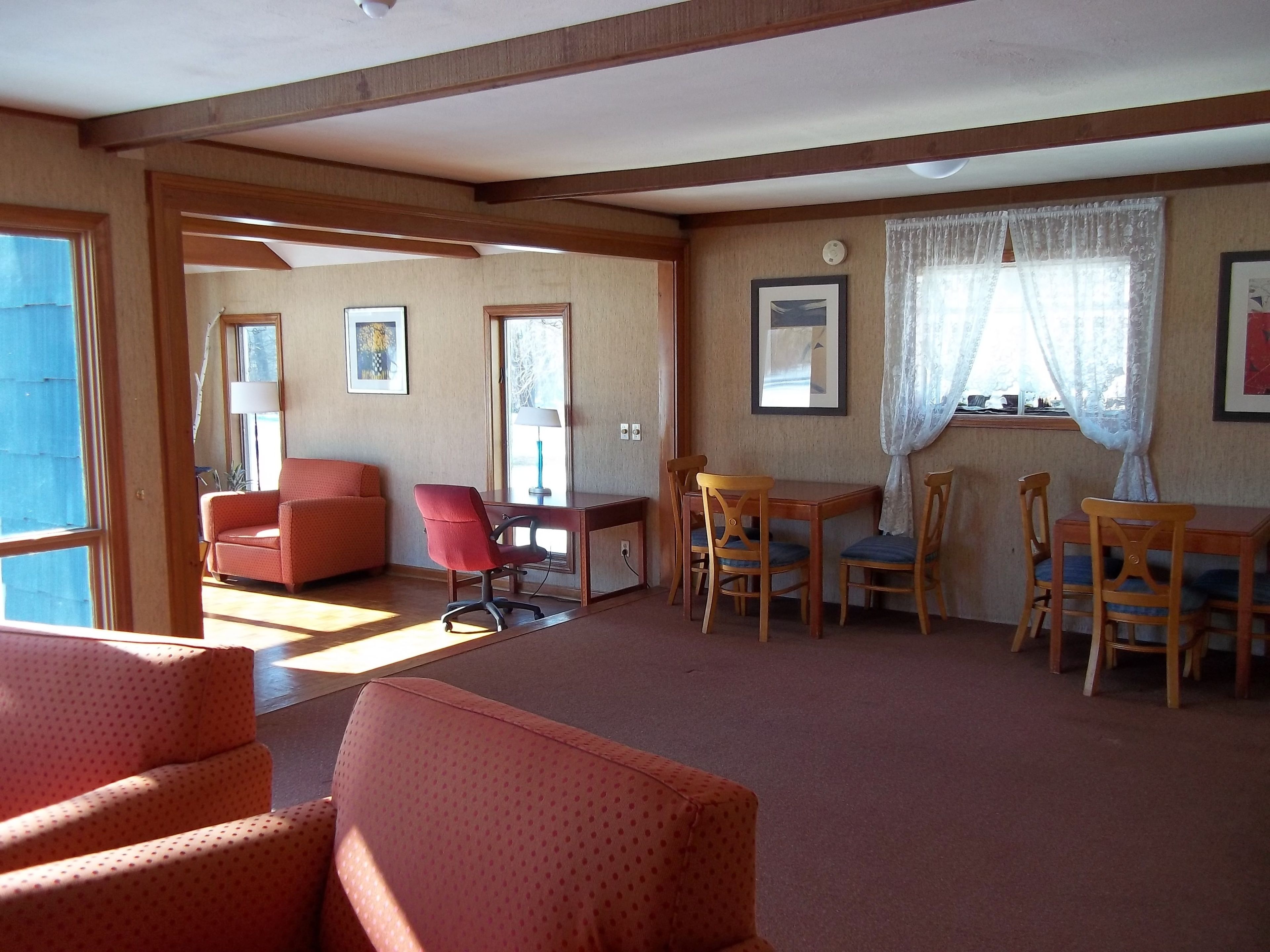 Amplia sala de estar con sofá, mesa de comedor y sillas, y una ventana con cortinas.