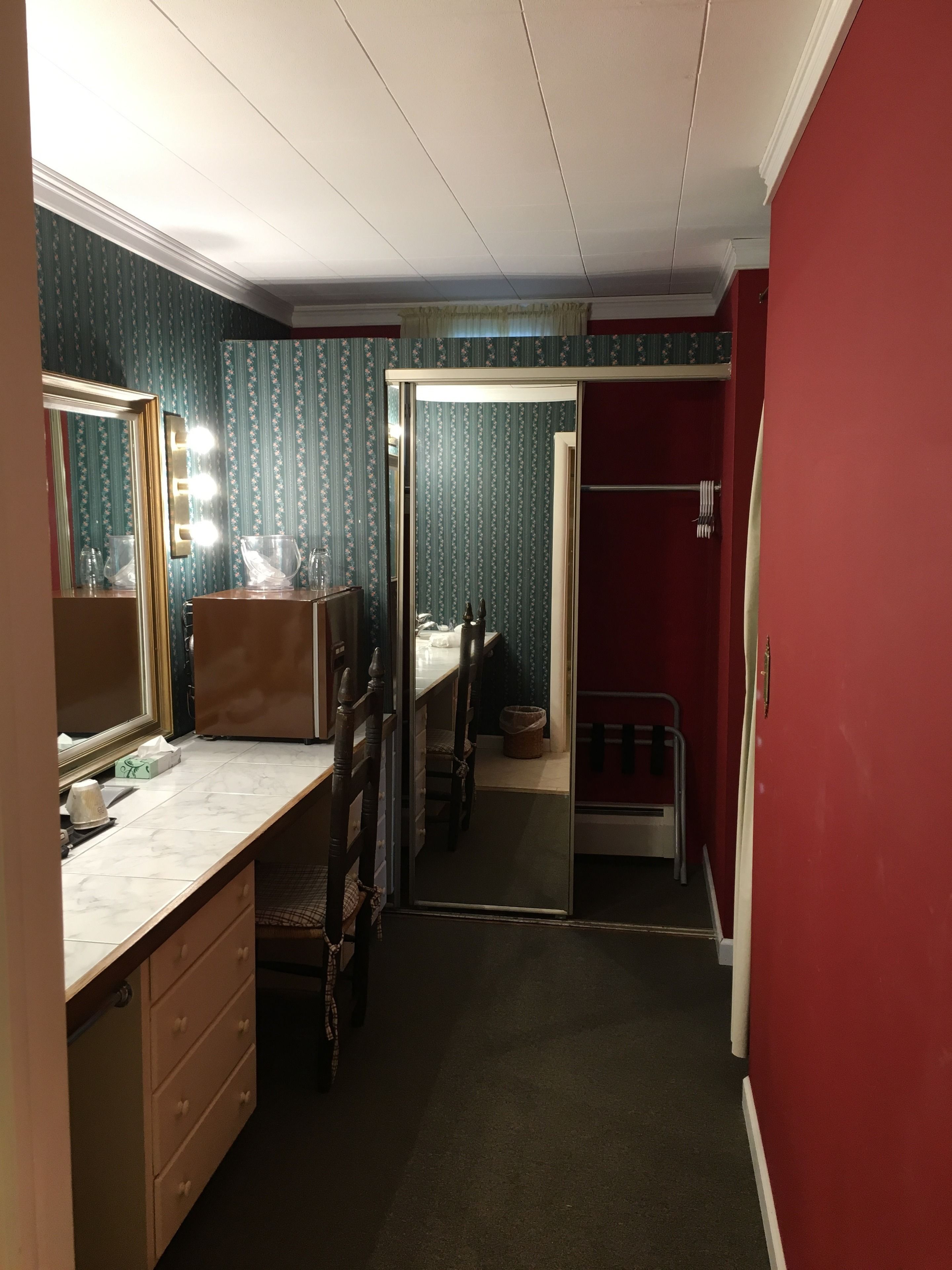 Une pièce comprenant une coiffeuse, un miroir et une porte donnant sur un placard.