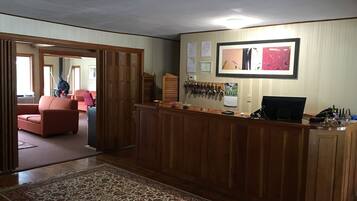 A reception area with a wooden desk, a computer, and a wall-mounted key rack.