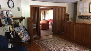A room with a wooden floor, a patterned rug, a wooden desk with a chair, and a wall clock.