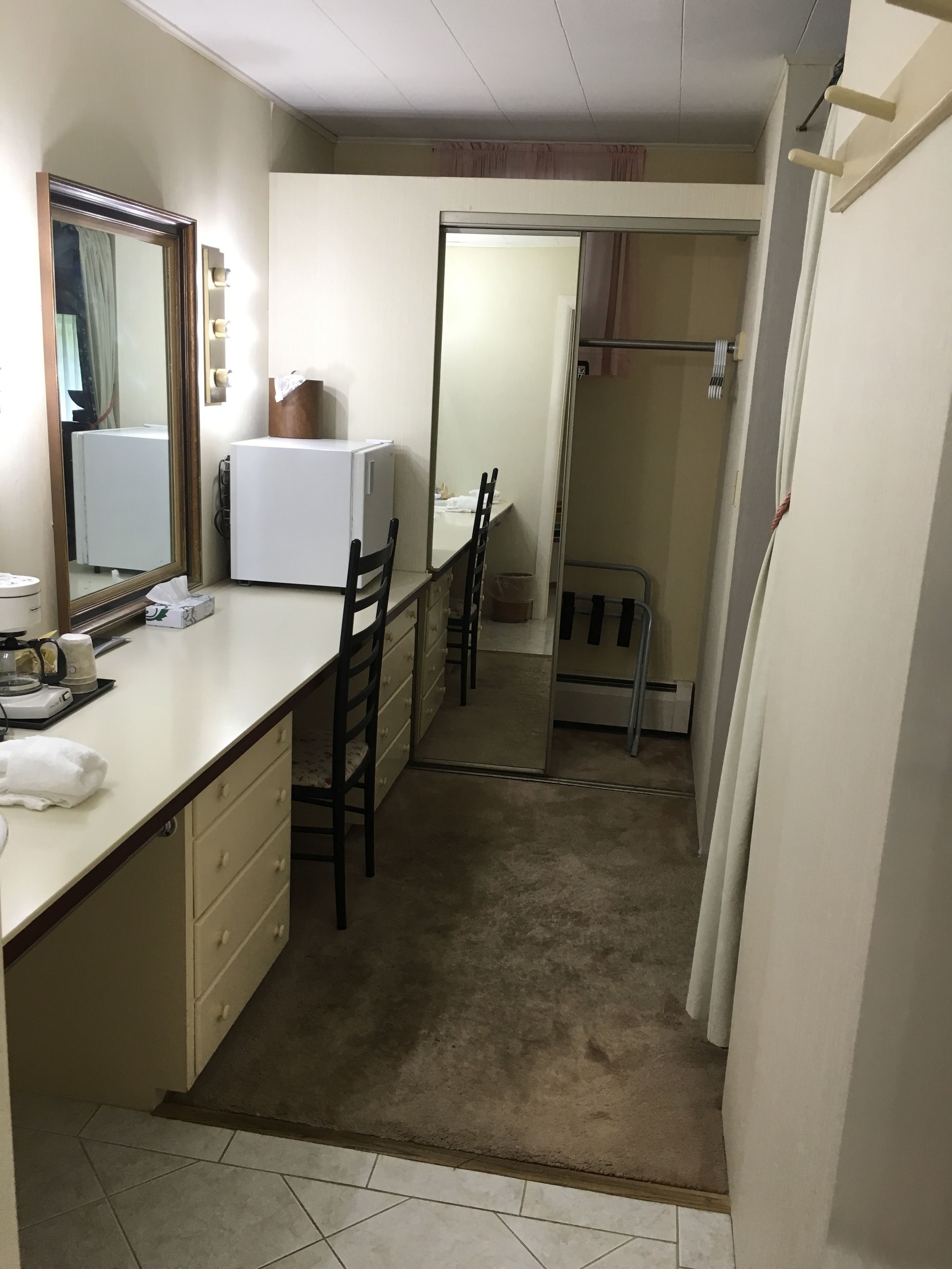 A compact hotel room with a kitchenette, a small dining area, and a shower.