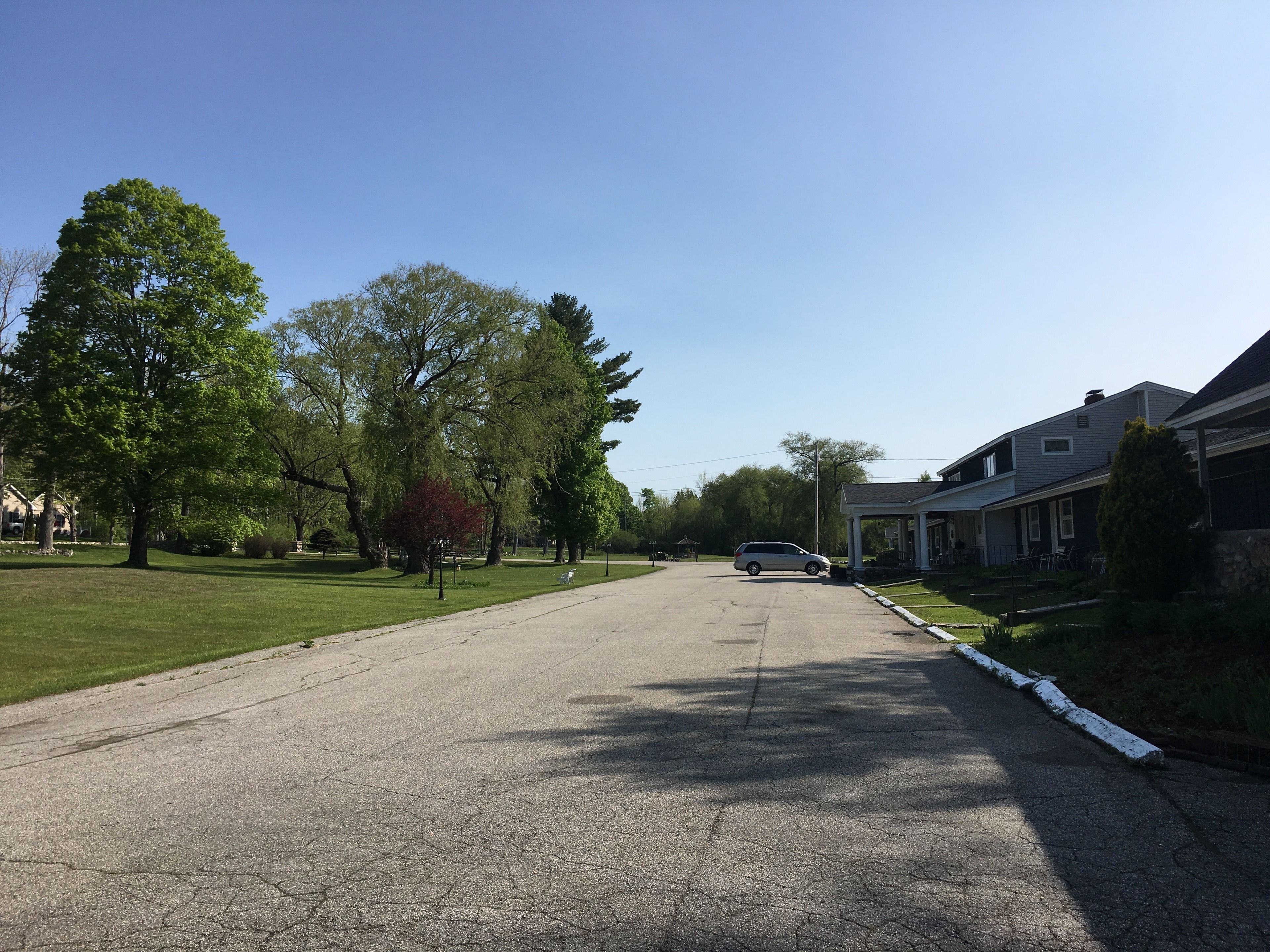 A residential street with houses, a driveway, and a parked car.