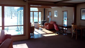 A spacious living area with large windows, a fireplace, and a dining table.