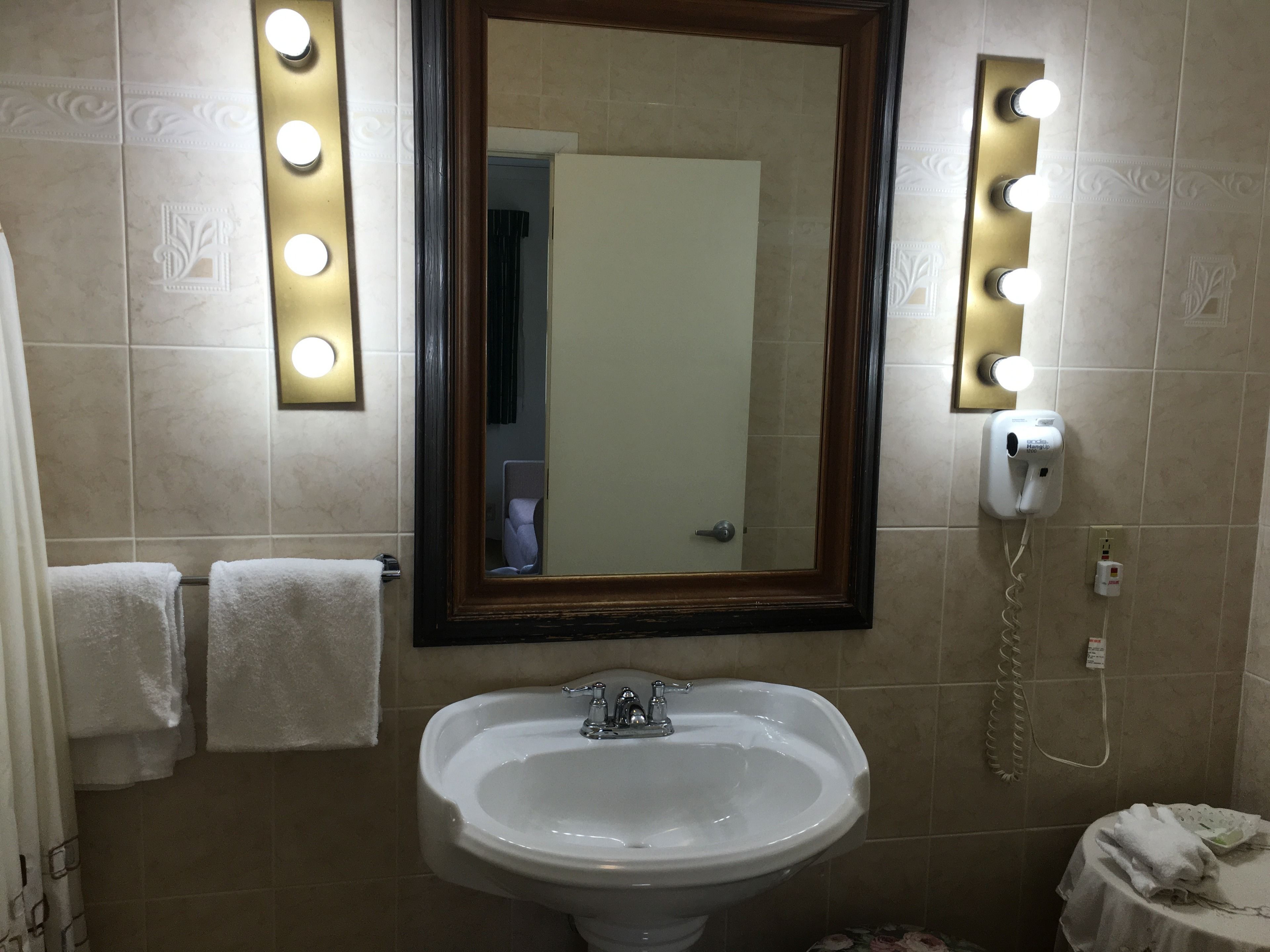 A bathroom with a sink, mirror, and lights.