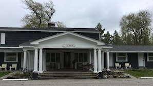 A building with a sign reading "OFFICE" at the entrance, featuring a porch with columns and a covered entryway.