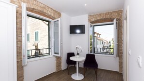 Una habitación pequeña con dos sillas, una mesa y un televisor montado en la pared.
