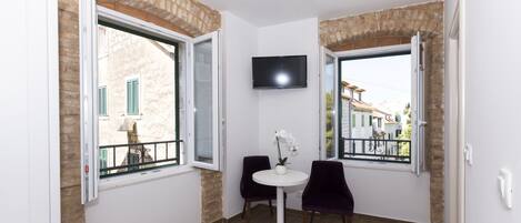 Una habitación pequeña con dos sillas, una mesa y un televisor montado en la pared.