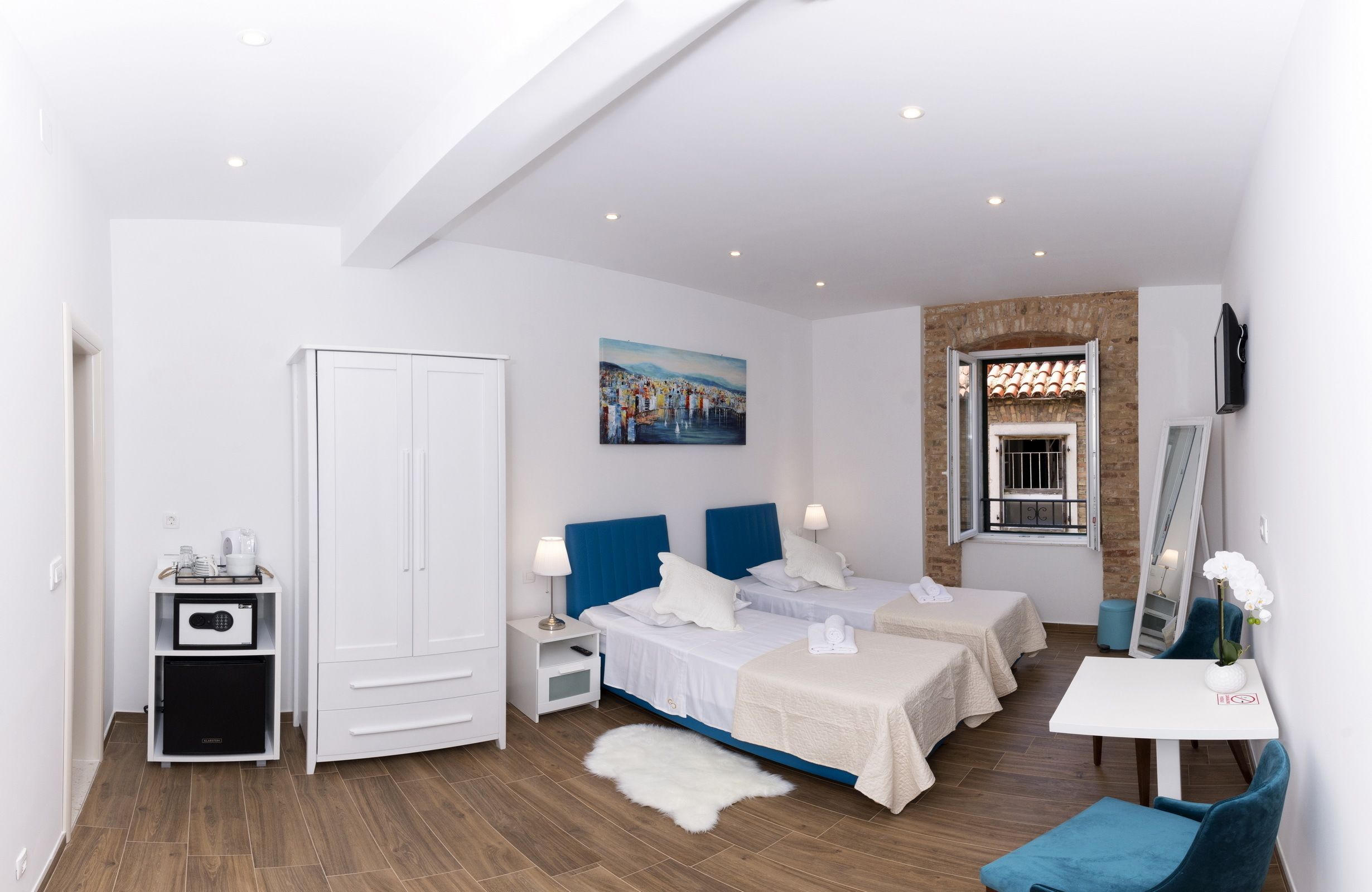 Een moderne hotelkamer met een groot bed, twee nachtkastjes, een bureau, een kledingkast en een schilderij aan de muur.