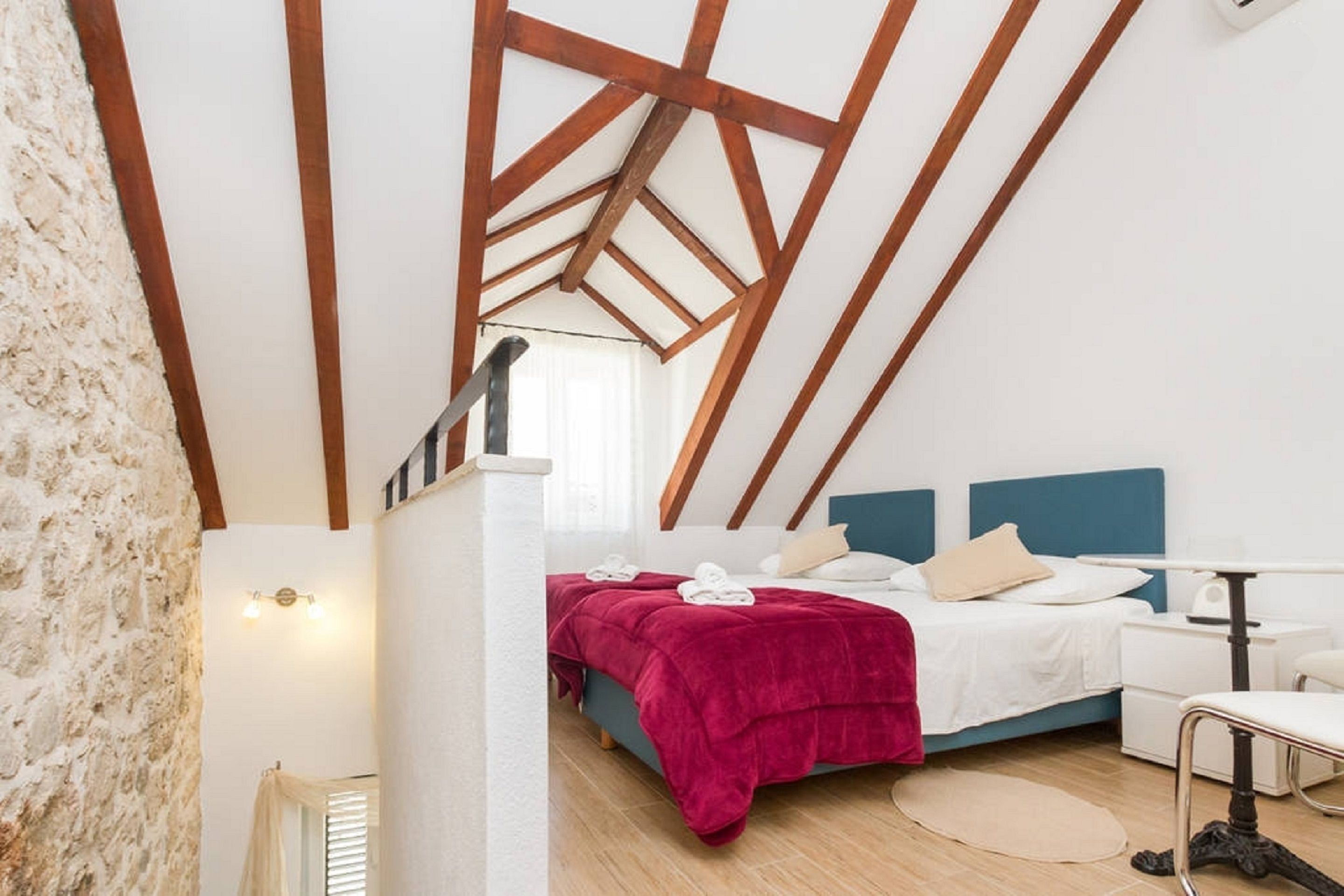 A bedroom with a bed, bedside table, and a desk with a chair.