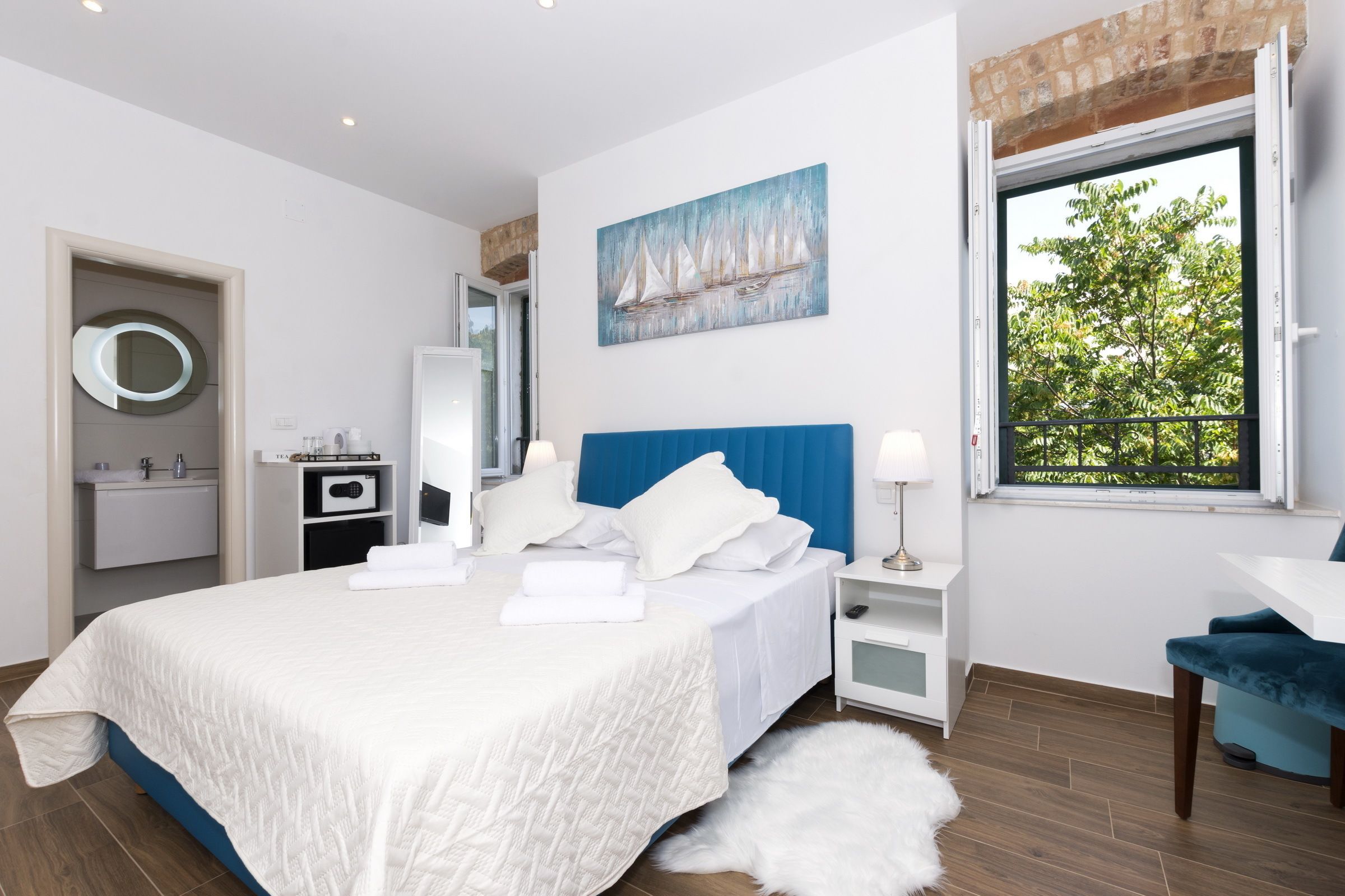 Een moderne slaapkamer met een groot bed, een nachtkastje, een stoel, een raam met uitzicht en een schilderij aan de muur.