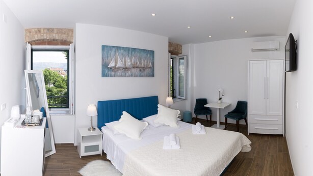 Un dormitorio moderno con una cama grande, un escritorio, una silla y un armario.
